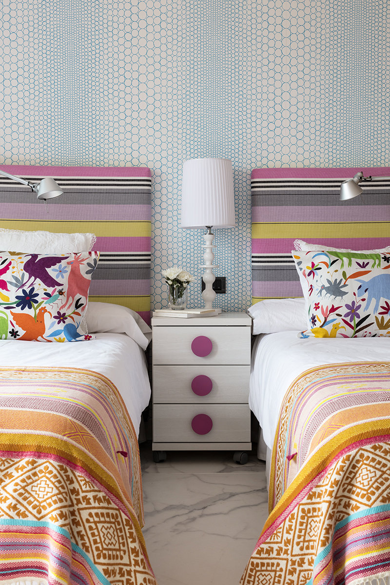 Dormitorio juvenil con cabeceros tapizados de rayas de coores. 