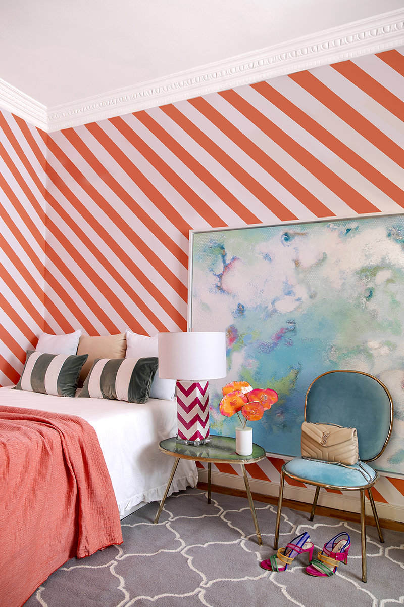 Dormitorio juvenil con papel pintado de rayas oblucias y cuadro grande.