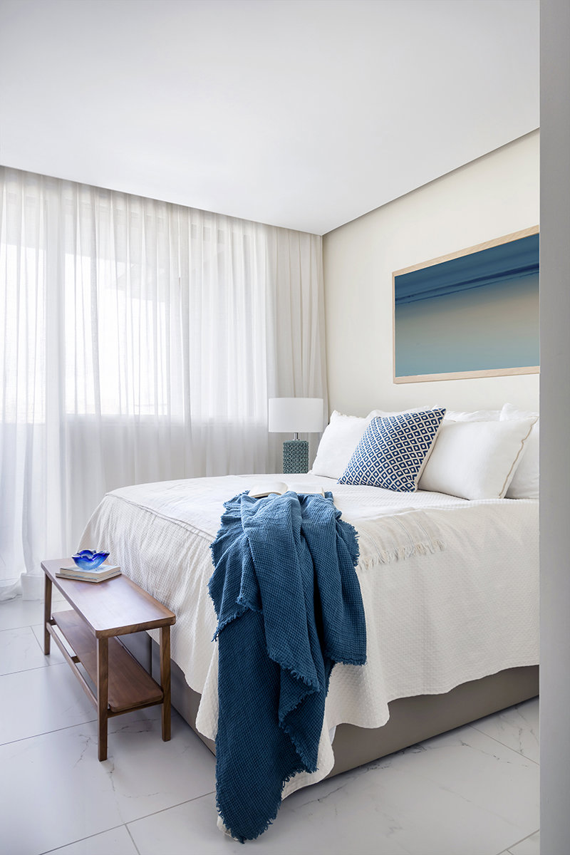 Dormitorio de matrimonio con ropa de cama blanca y zcuadro azul. 