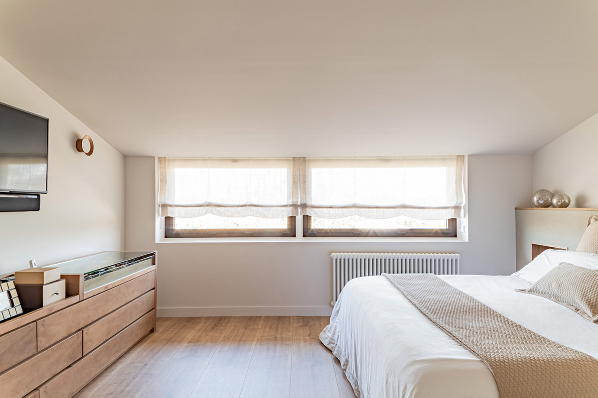 Dormitorio matrimonio con cómoda de madera alargada. 