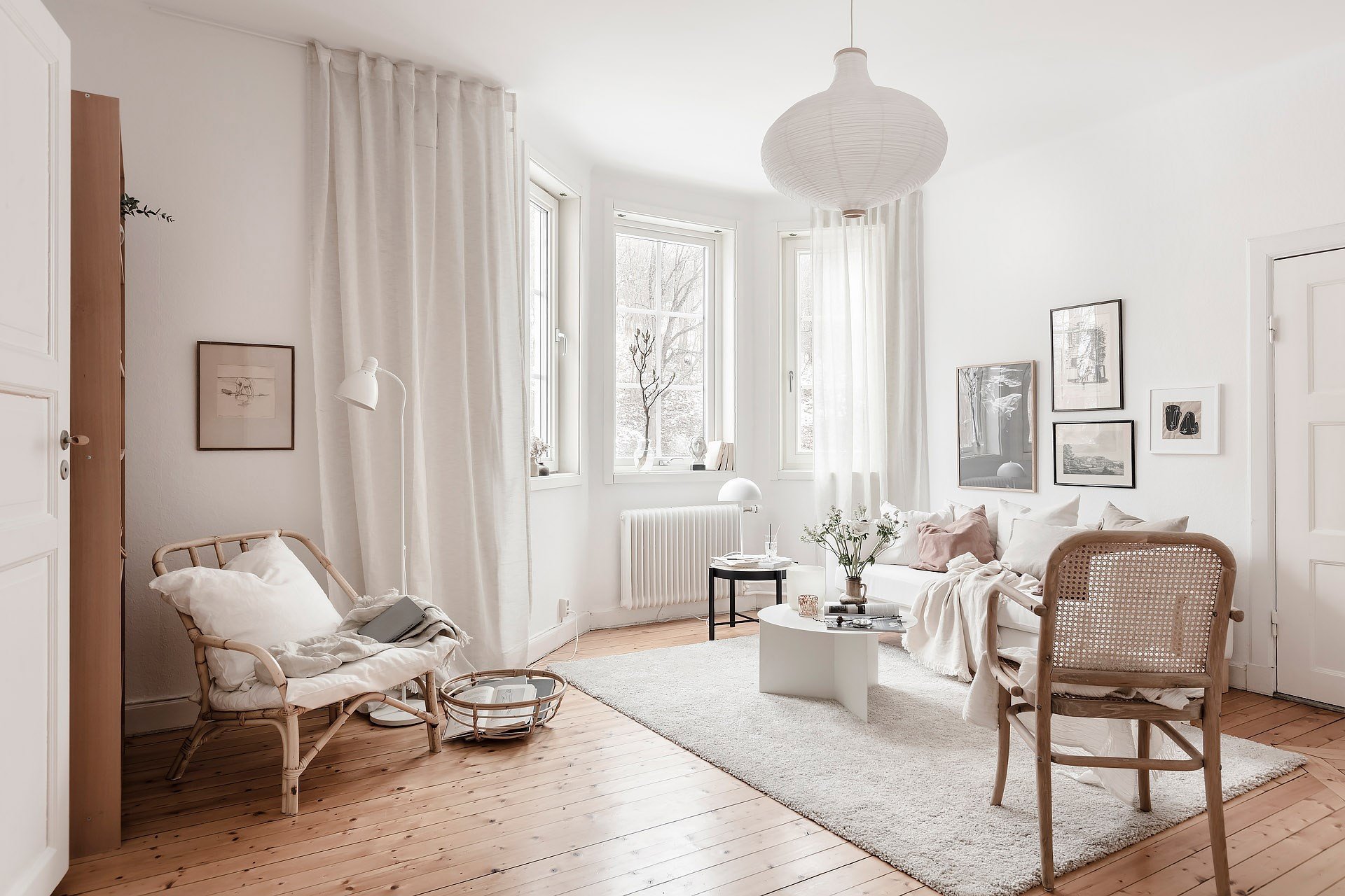 Salón de estilo nórdico lleno de luz gracias a los ventanales y a una paleta de colores en tonos blancos.