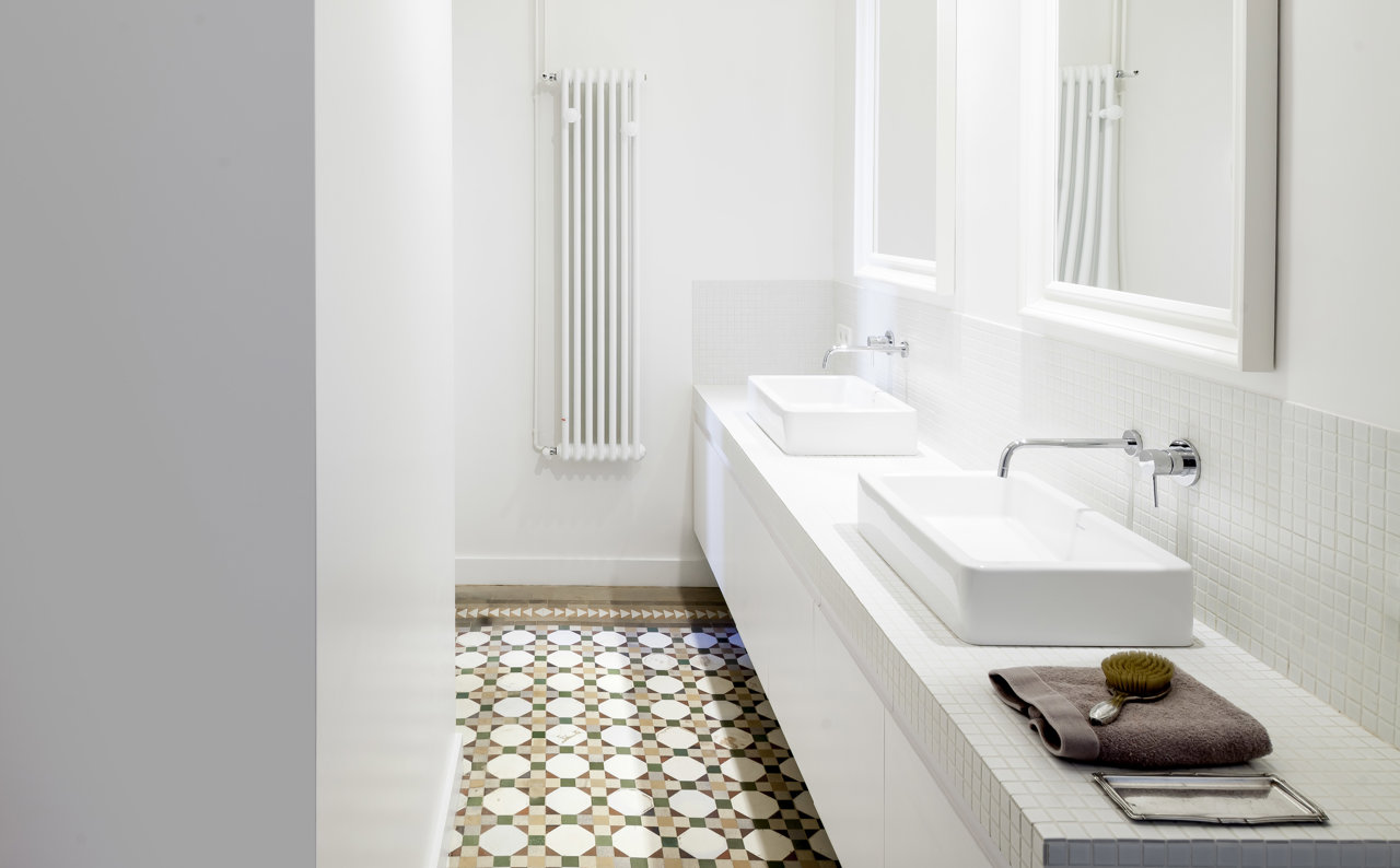 Un muro alto de yeso es la alternativa más moderna y de diseño para un baño que no quiere ni mamparas ni cortinas