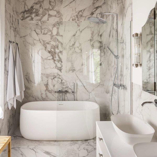 Baño con paredes de mármol y bañera exenta
