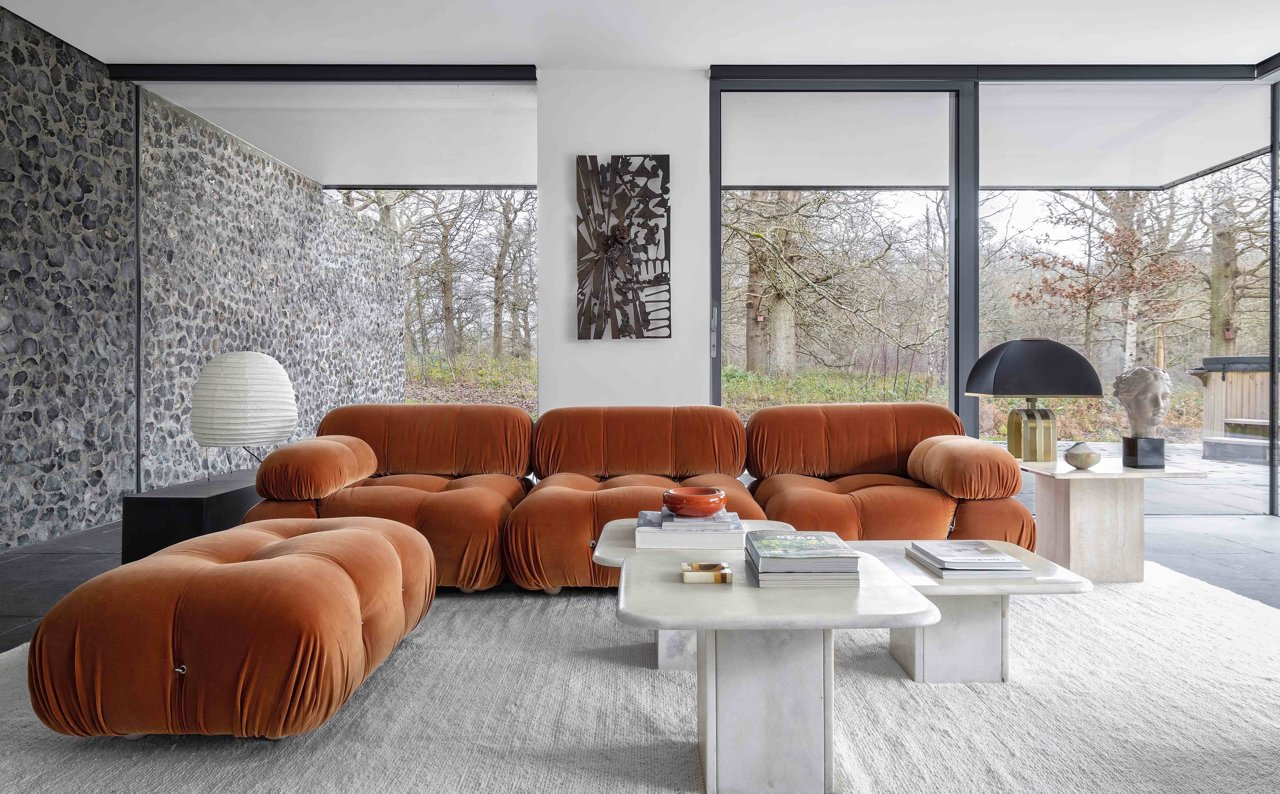 Salón con grandes ventanales y sofá de diseño color naranja caldera