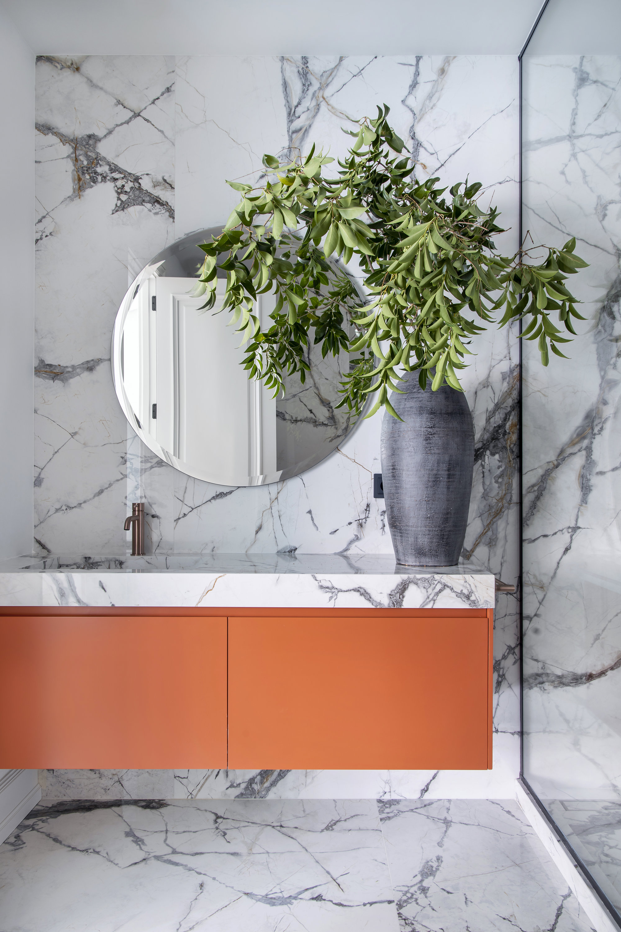 Baño moderno mármol y muebles naranjas