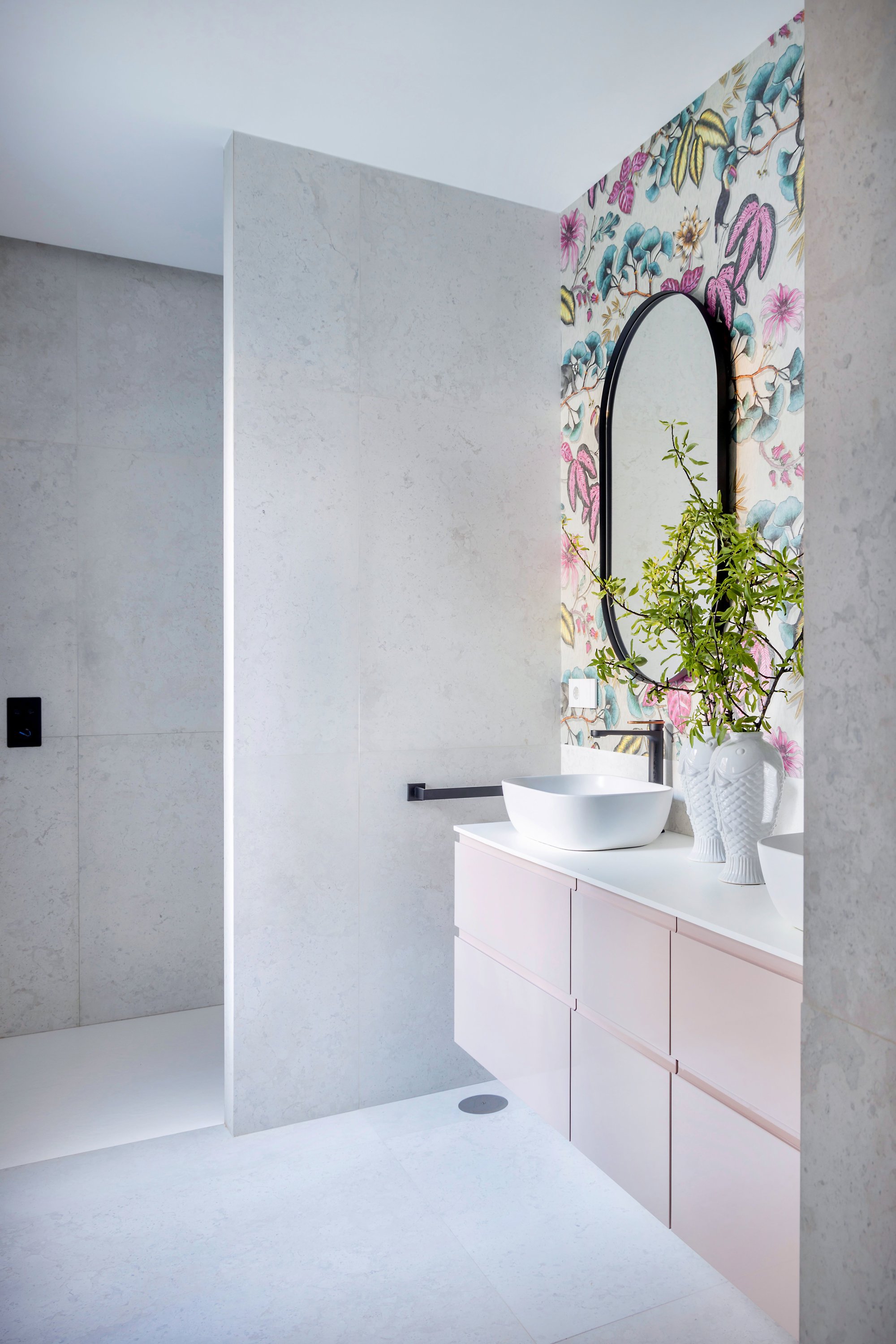 Muro separador en un baño en tonos rosas y gris claro.