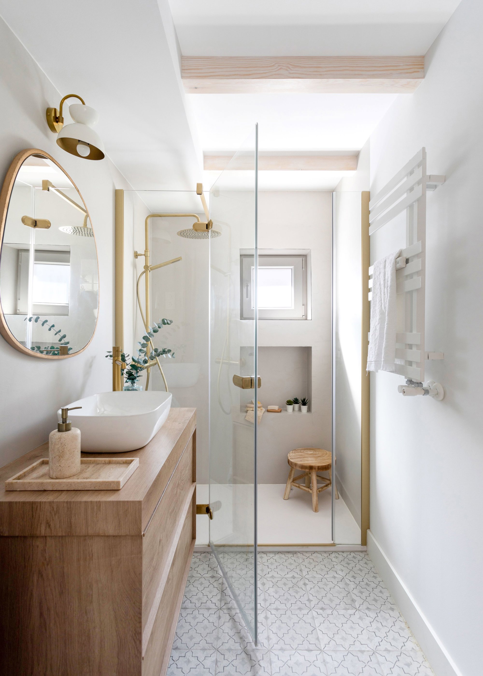 Un baño en tonos claros con detalles en oro y madera.