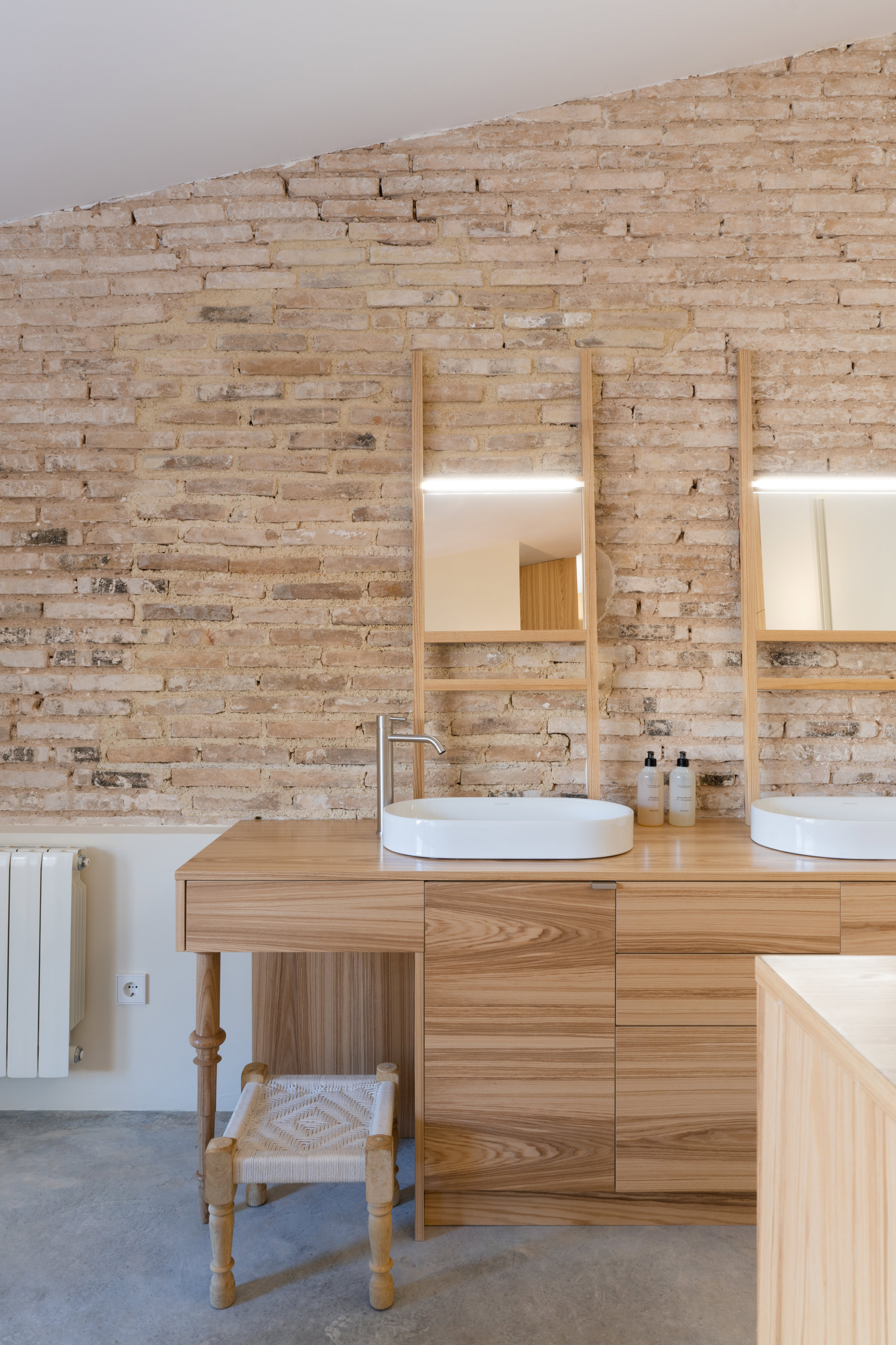 Un baño que combina la pared de piedra con el mueble bajo lavabo de madera. 