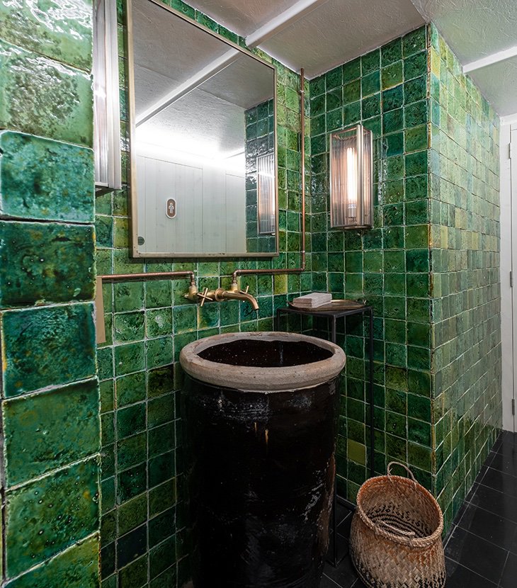 Baño con azulejos verdes del restaurante Corzo Iluzione, por Luzio Studio