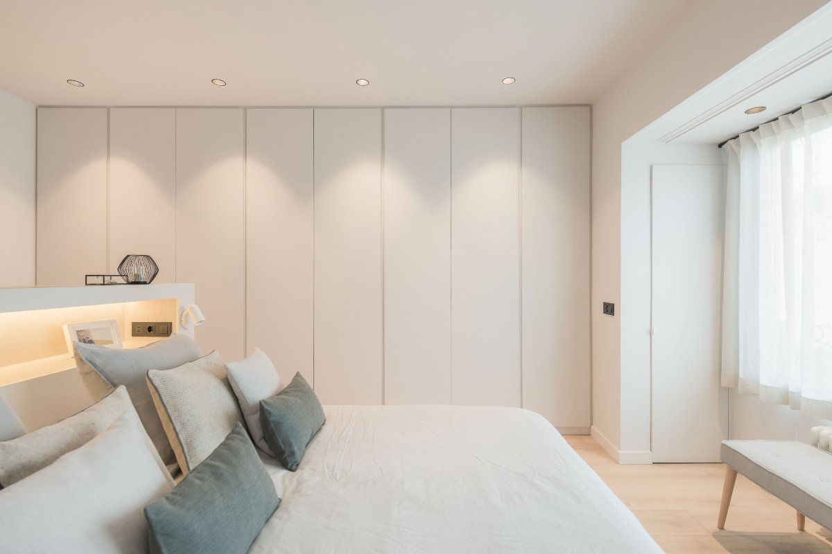 Dormitorio minimalista en tonos blancos y grandes armarios