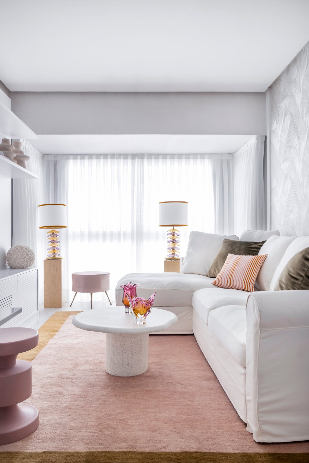 Salón con sofá blanco, alfombra rosa y lámparas de delicado diseño