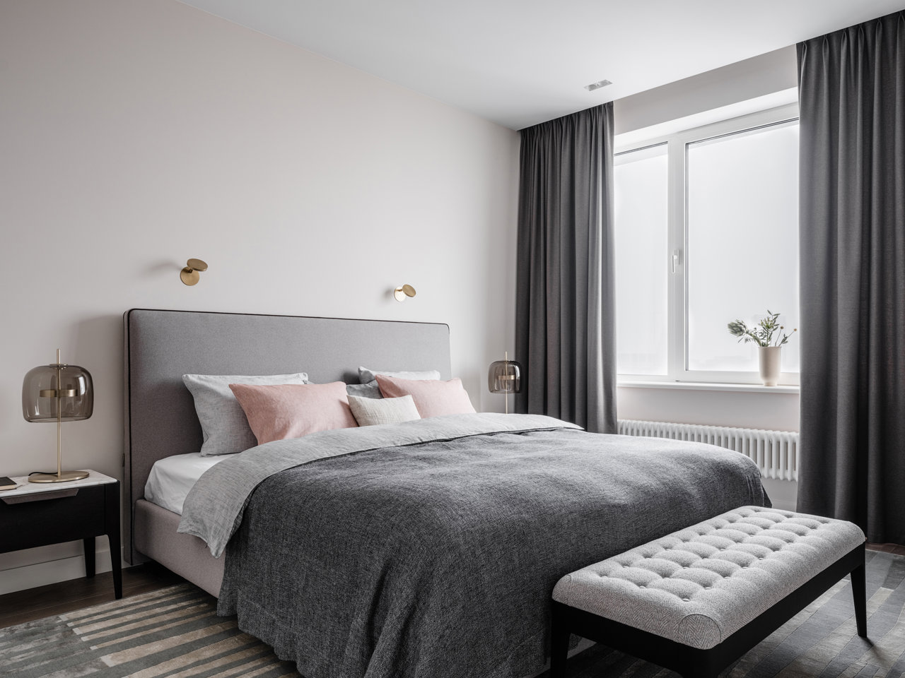 El detalle de unos cojines en tonos rosados rompe el monocromatismo gris del dormitorio principal y aporta un guiño más cálido.