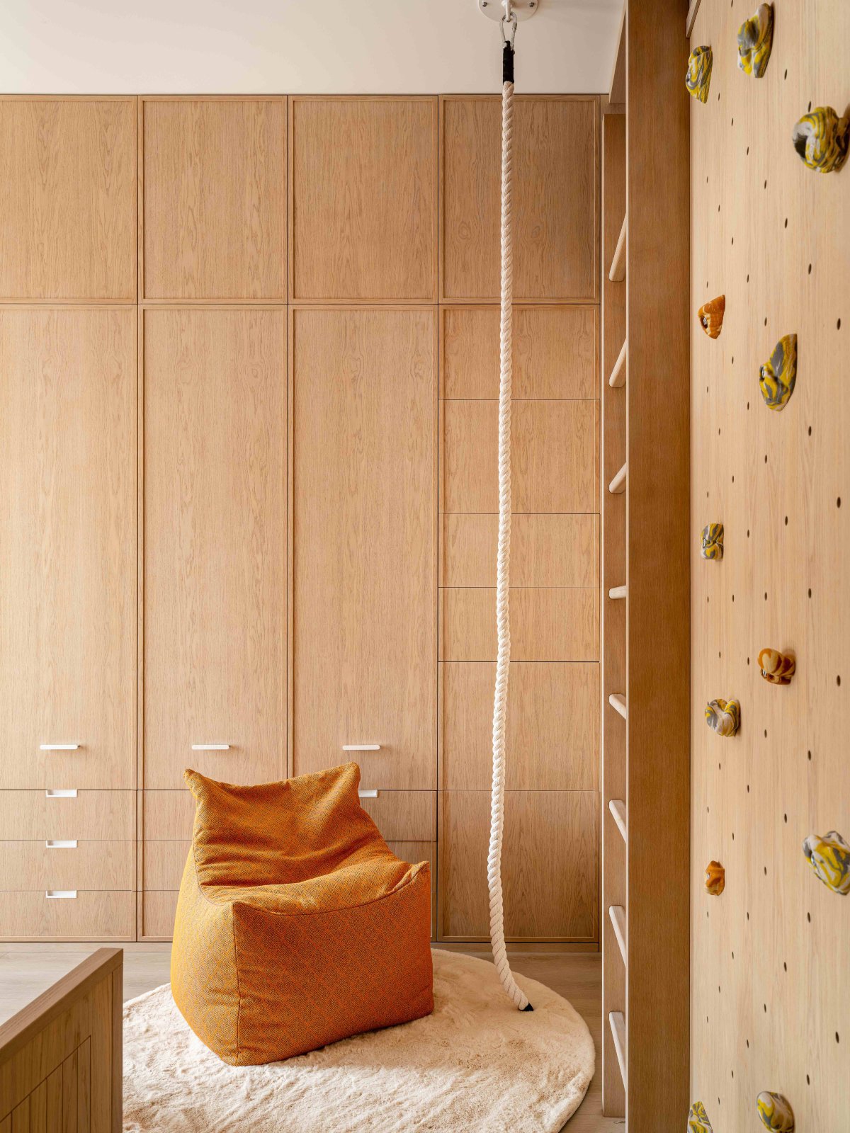 Habitación panelada en madera con rocódromo en una de sus paredes