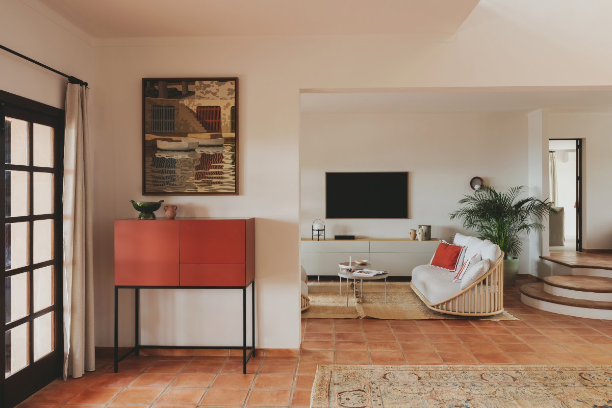 Salón pequeño con aparador en rojo, alfombra y suelo de terrazo