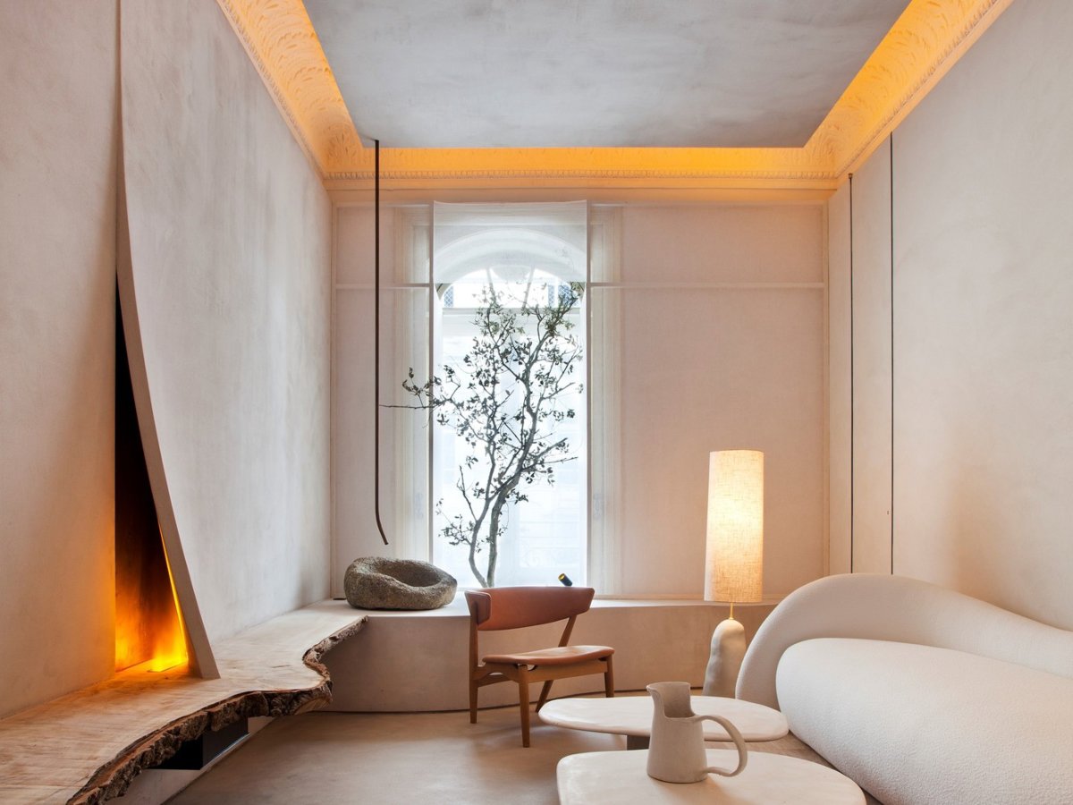 Salón pequeño con chimenea abierta, molduras iluminadas y sofá de formas orgánicas