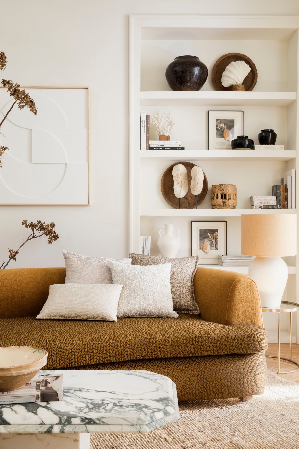Salón pequeño con sofá marrón, alfombra rústica y librería blanca de obra
