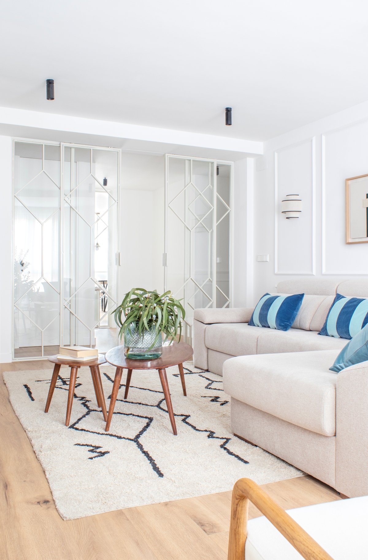 Salón pequeño con cojines azules, sofá gris y puertas correderas blancas