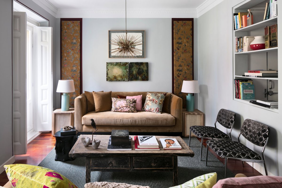 Salón pequeño con mesa envejecida, sofá de terciopelo marrón y cojines florales