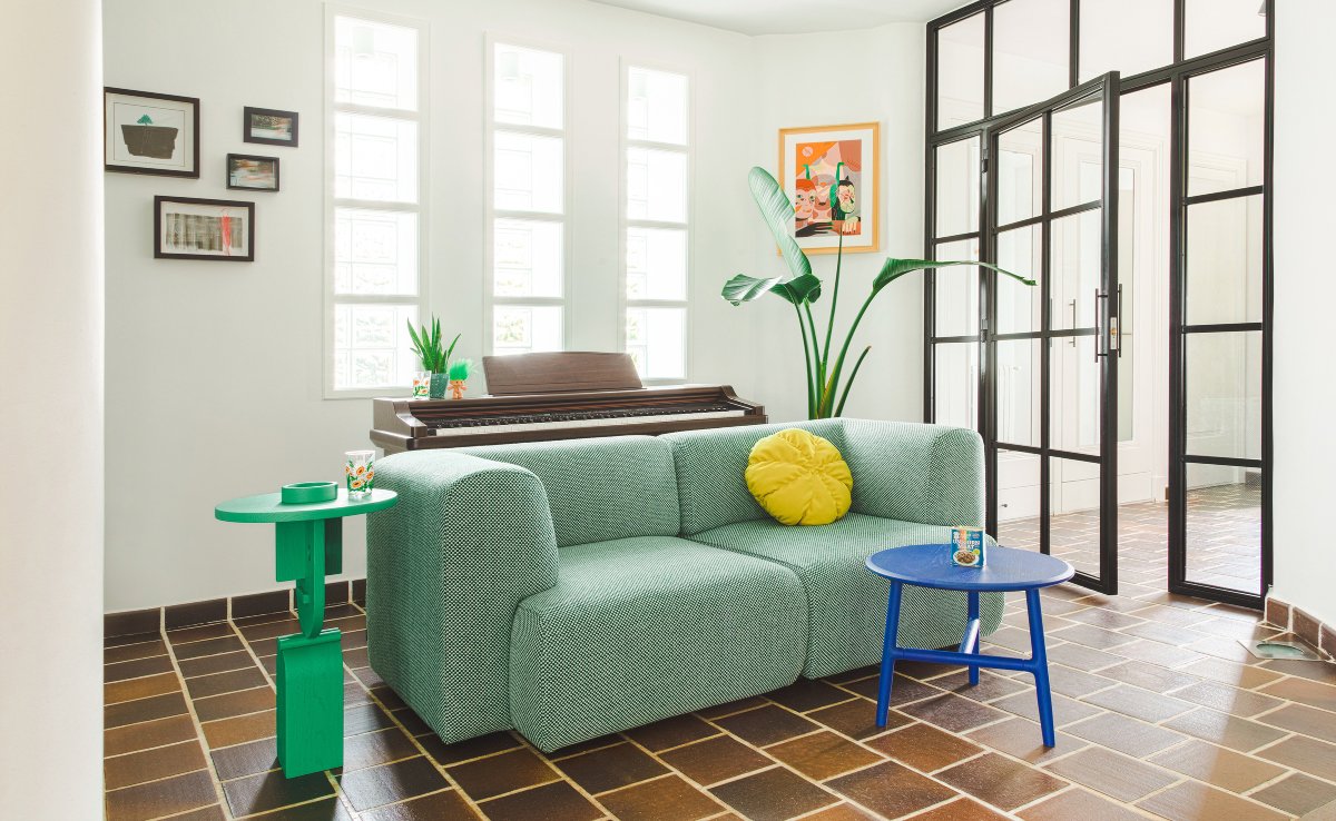 Salón pequeño con sofá verde, cojín amarillo y mesita azul
