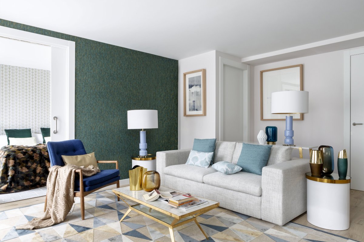 Salón pequeño con pared verde, sofá gris y elementos en dorado