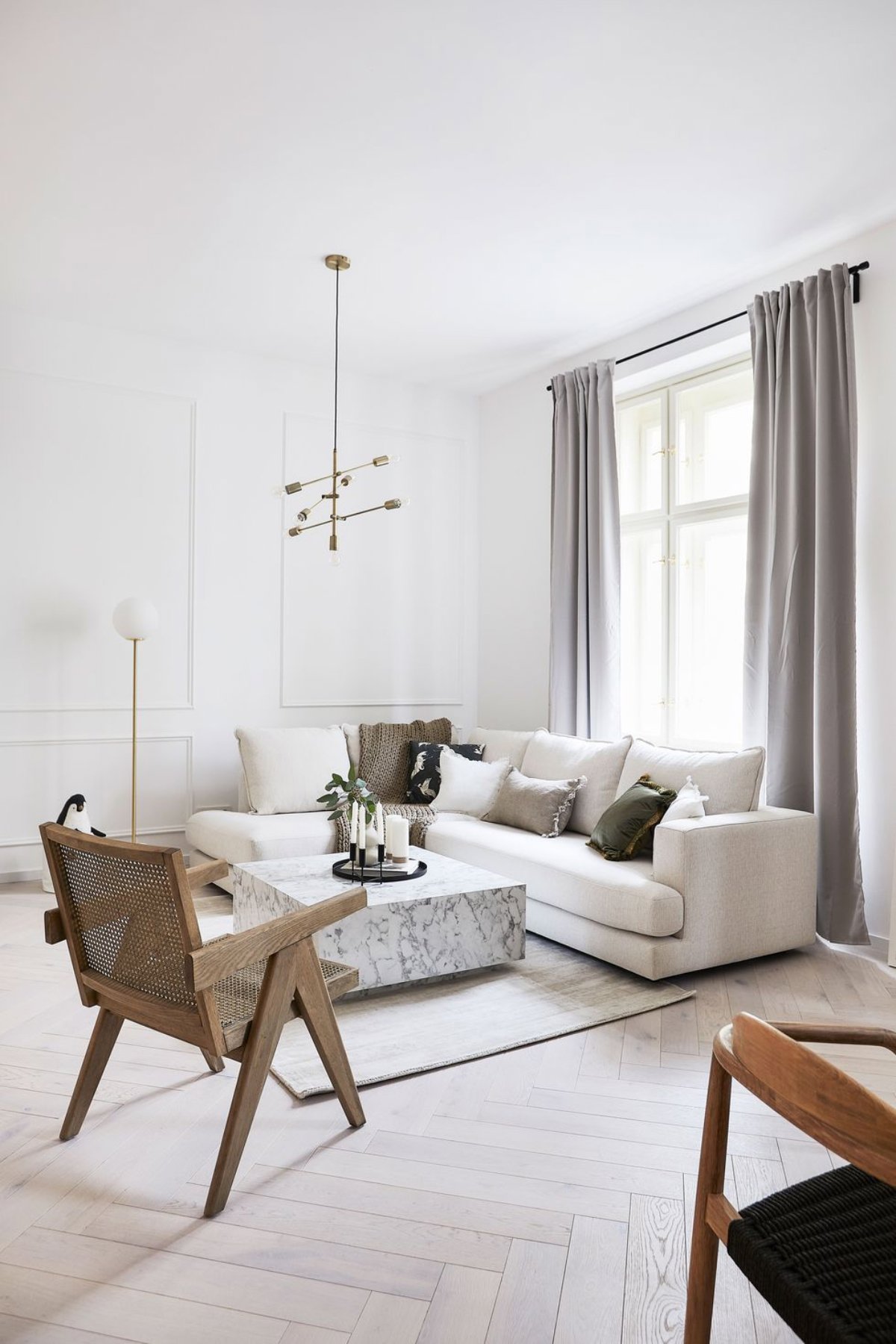Salón pequeño con sofá blanco, cortinas grises y mesa de mármol