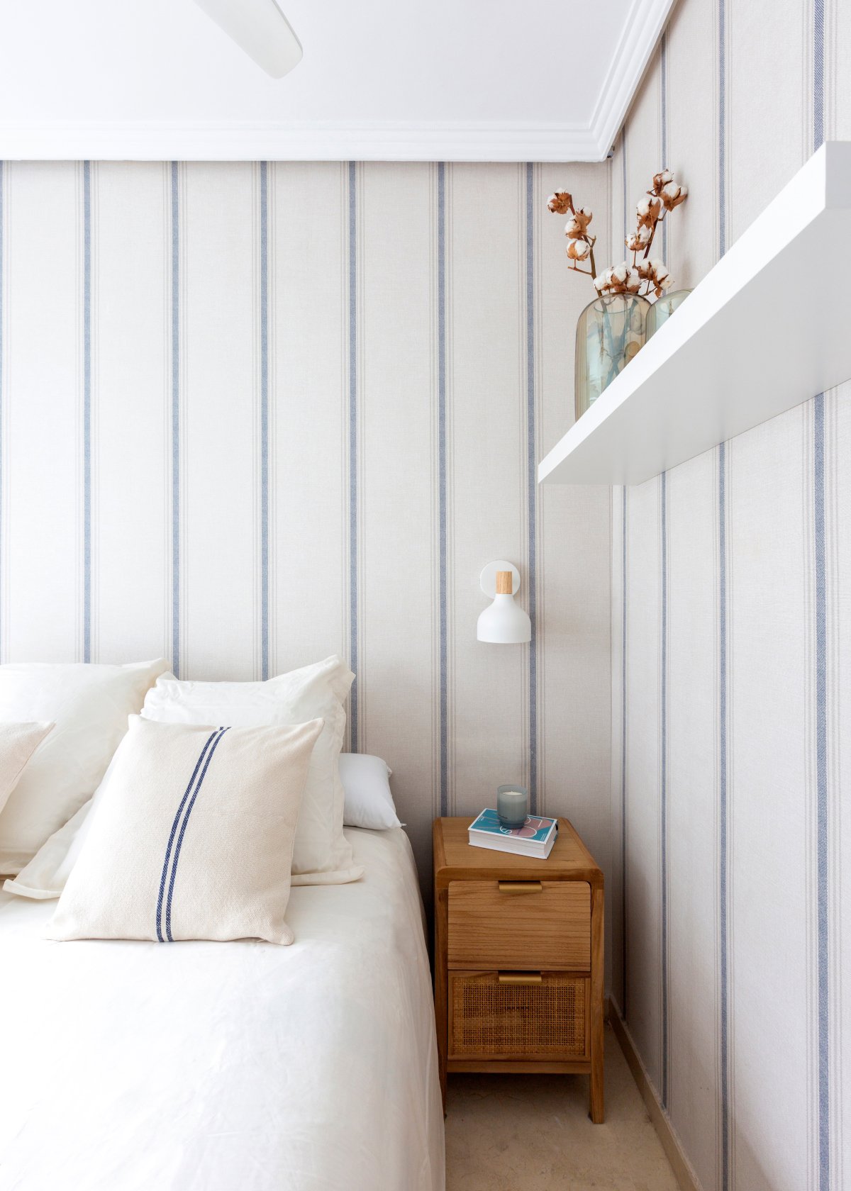 Dormitorio con ropa de cama blanca y papel pintado de rayas azules