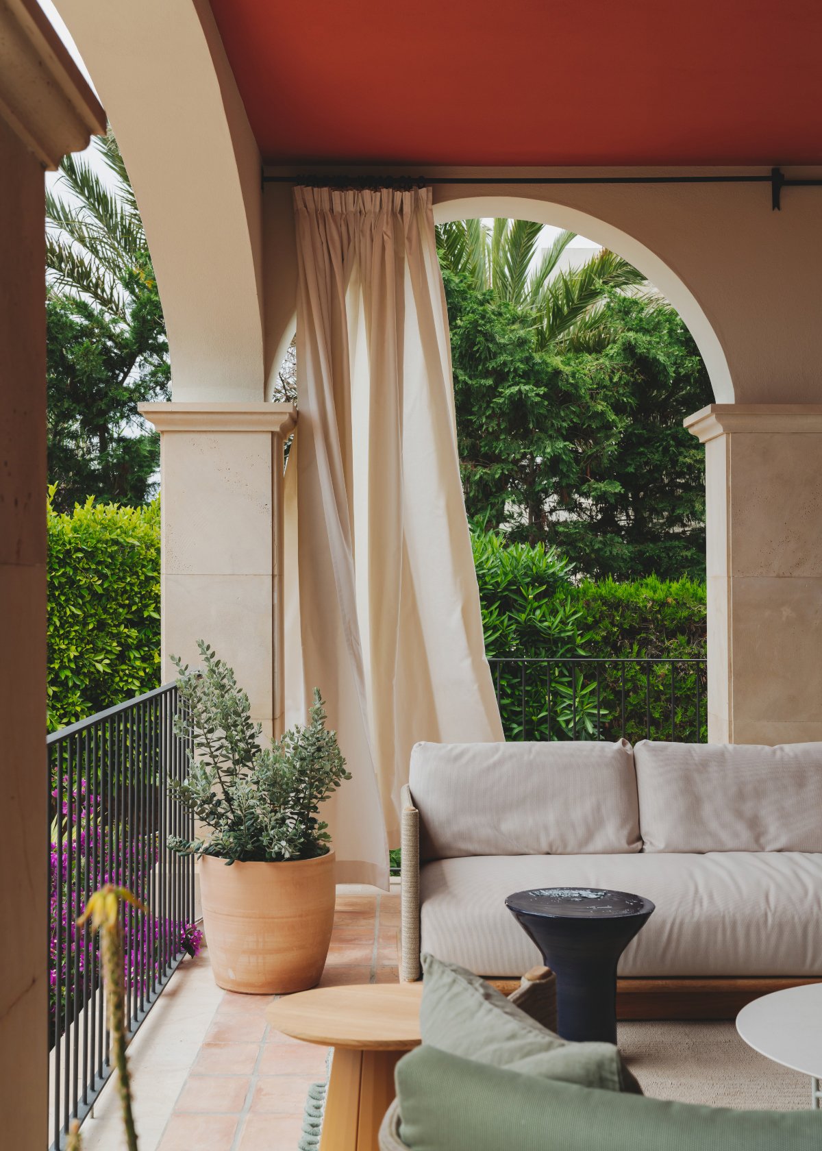 Terraza mediterránea con cortina y sofá en crudo