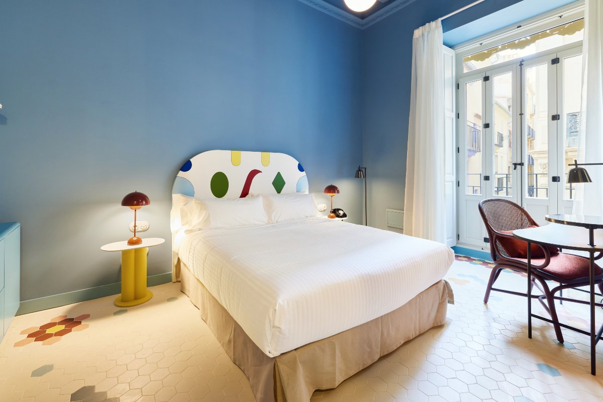 Dormitorio con cabecero de formas geométricas y paredes en azul