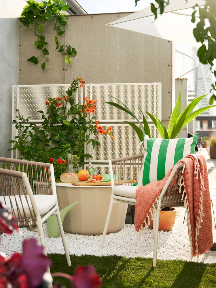 Terraza con sillas blancas sobre piedra del mismo color y césped artificial