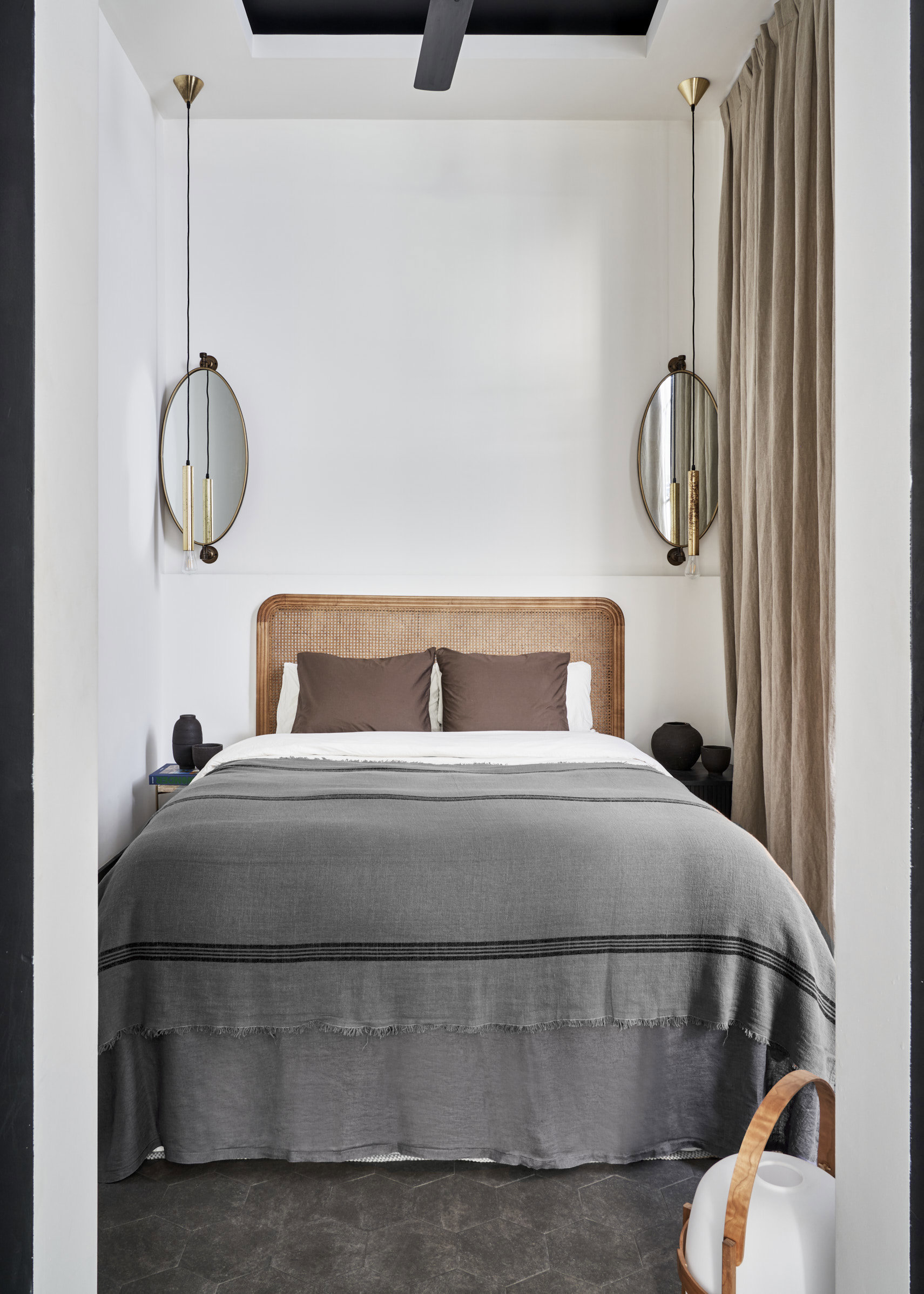 Dormitorio de cama de textil gris, espejos y lamparitas colgantes