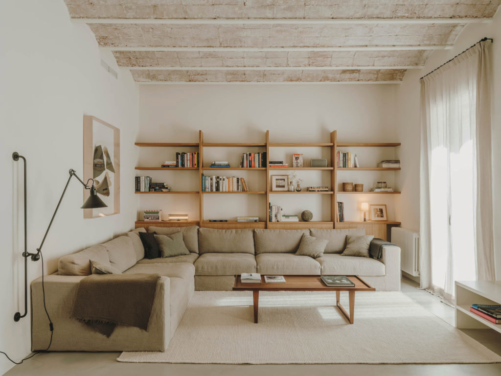 Salón de sofá esquinero y amplia librería de madera