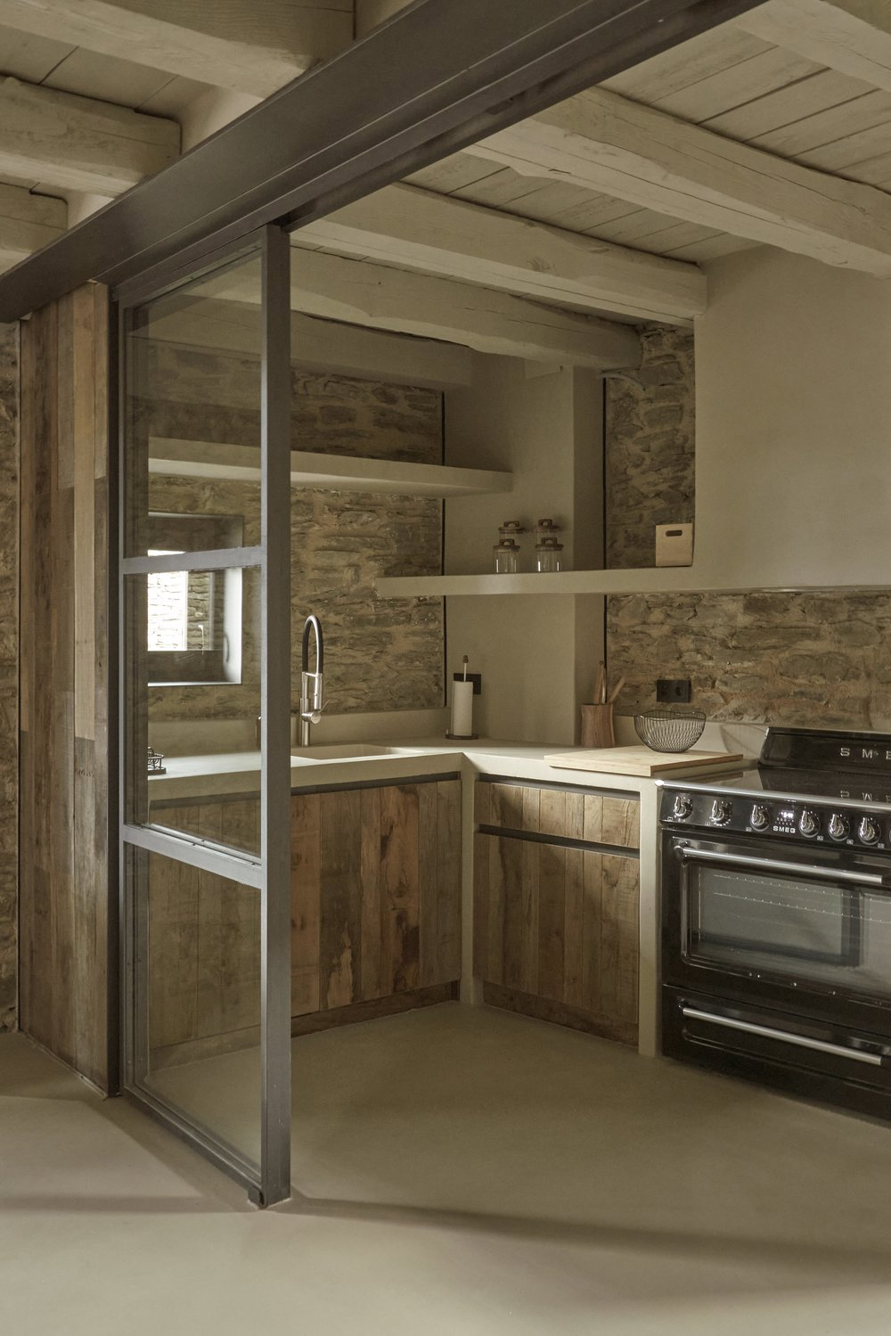 Cocina abierta de madera y pared de piedra