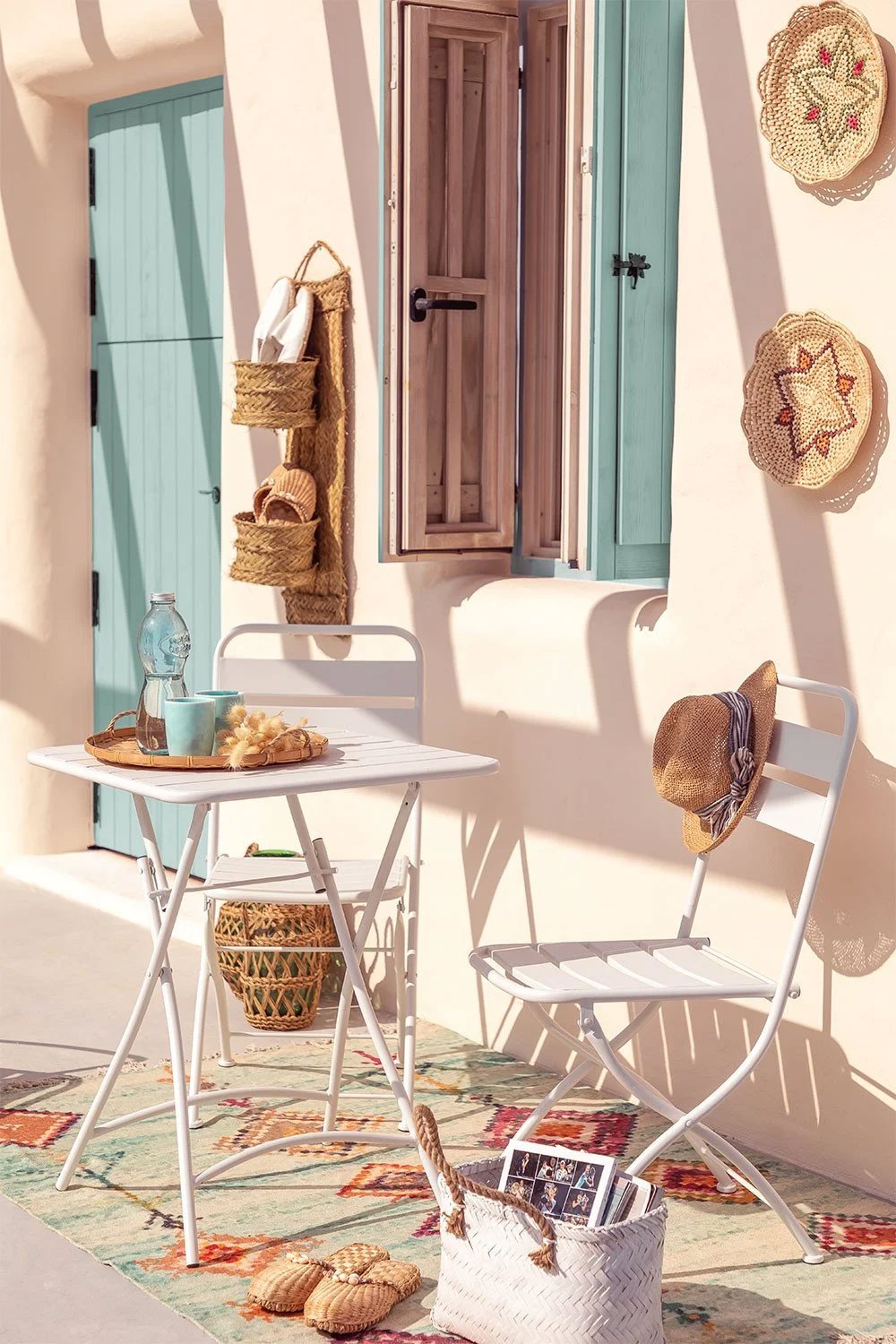 Terraza mediterránea con sillas y mesa blancas y elementos de ratán
