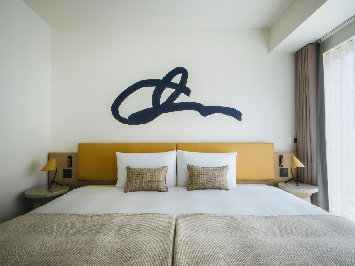 Trazo minimalista pintado en la pared de este dormitorio de cabecero amarillo