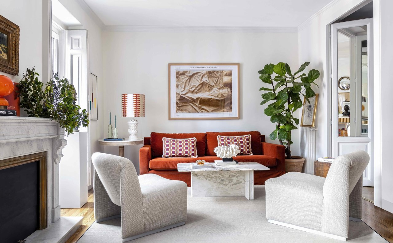 En este salón blanco de estilo clásico, el sofá en color rojo y la fotografía de la pared acaparan todo el protagonismo.