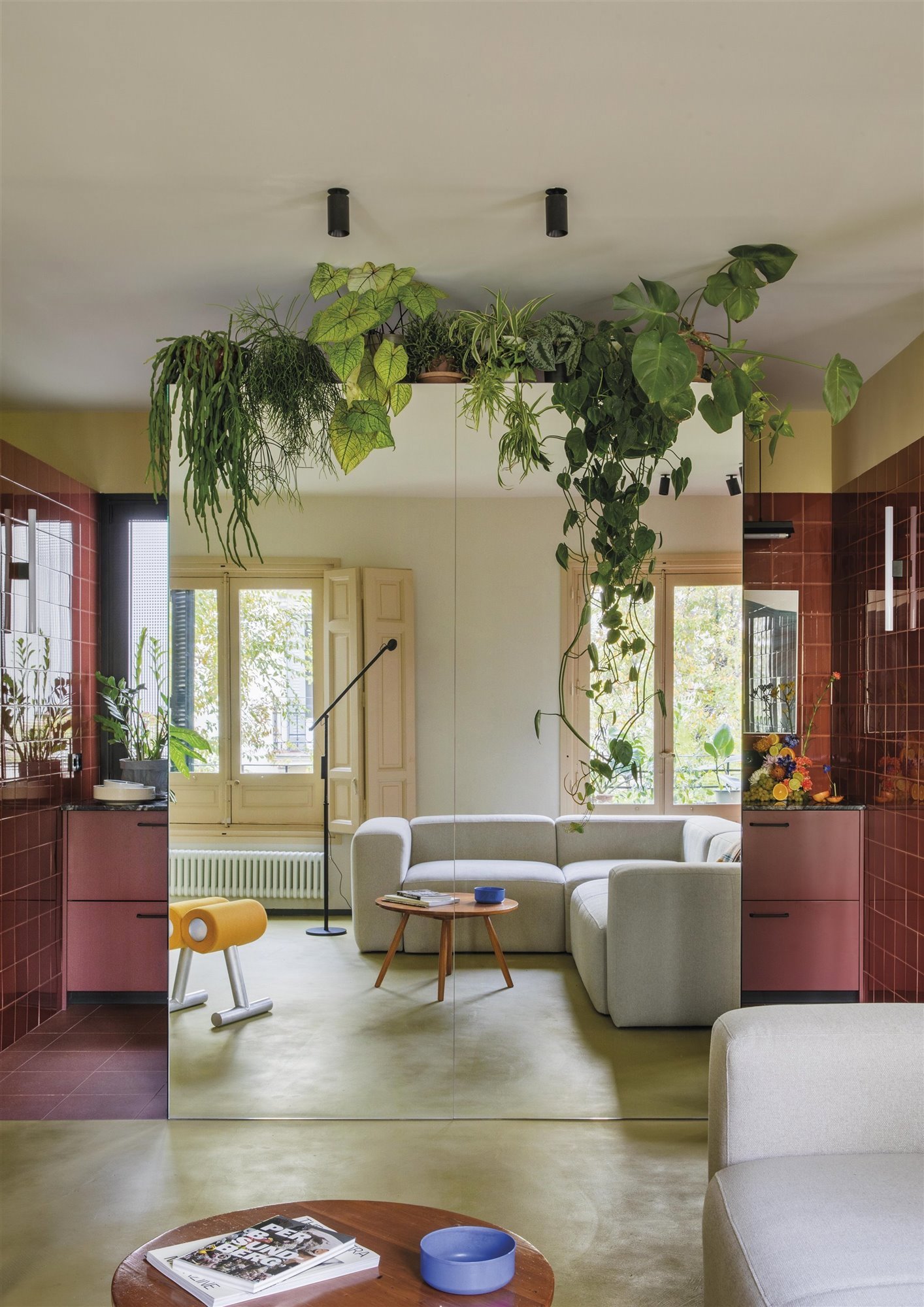 La cocina de este piso, diseñado por Estudio Reciente, se 'oculta' del salón con un espejo decorado con plantas.