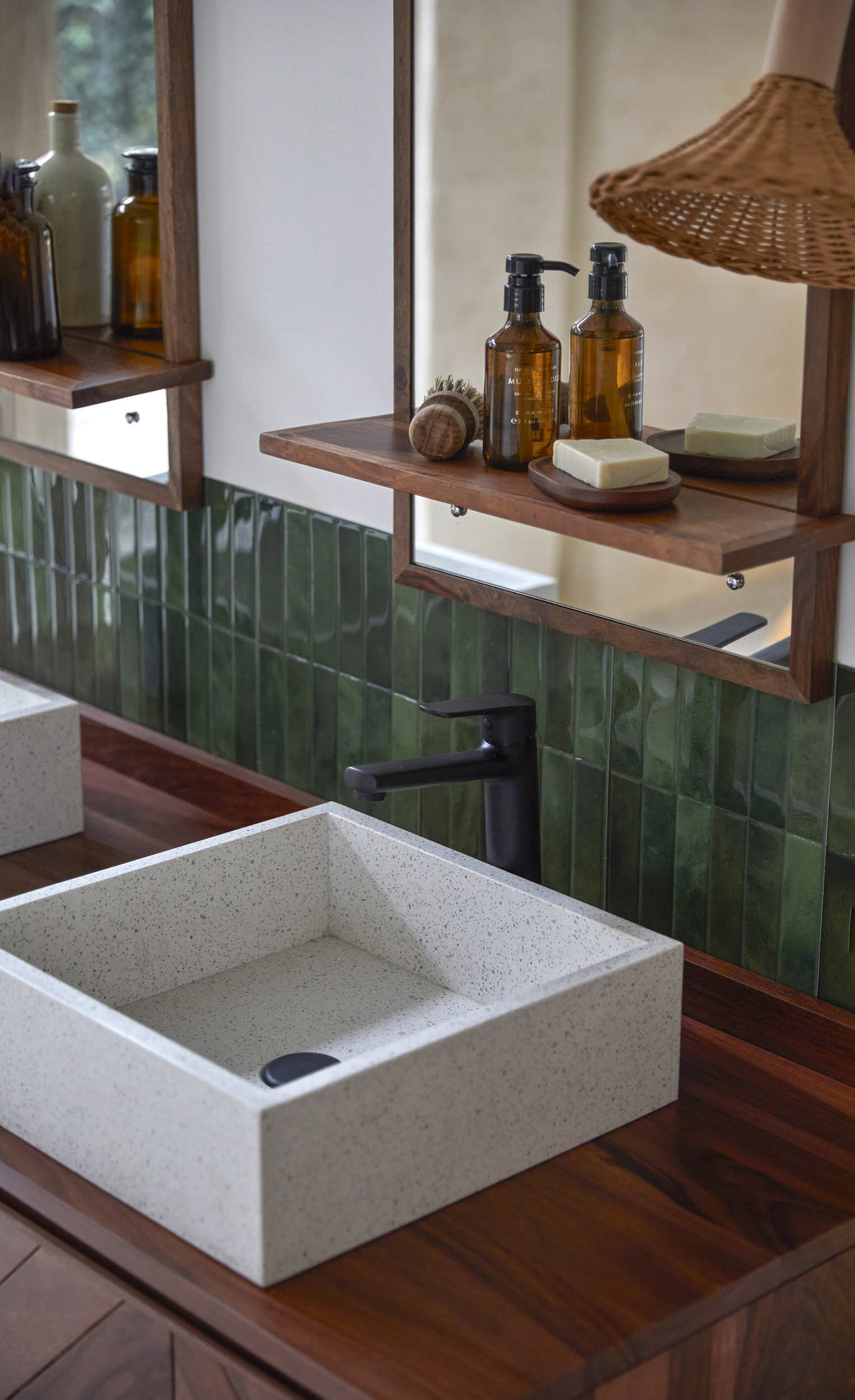 Baño con azulejos verdes, lavabo cuadrado y espejo con repisa de madera