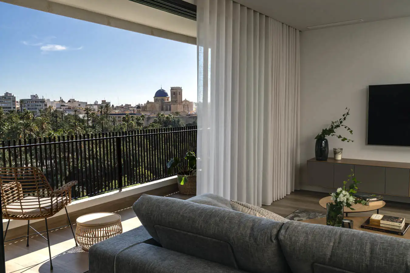 Las vistas sobre el Palmeral y la Basílica de Santa María de Elche son uno de los atractivos de la vivienda. En la terraza, butaca y mesa auxiliar de fibras, de Noble Interiorismo.