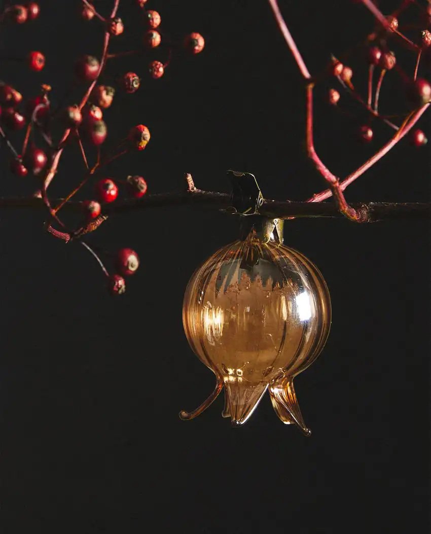 Este adorno de Navidad elegante mezcla la madera con el dorado de la bola en forma de granada