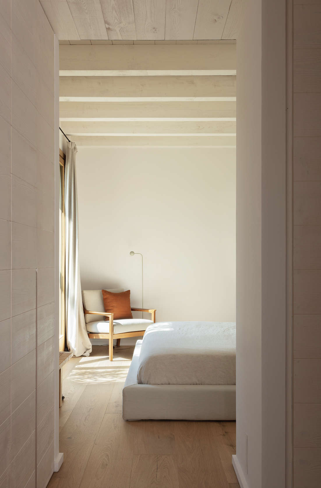 SUITE PRINCIPAL. Situada en la planta baja de la vivienda, la habitación incluye una butaca de Mia Collection a los pies de la cama. La base de ésta se diseñó con estructura tapizada en lino.