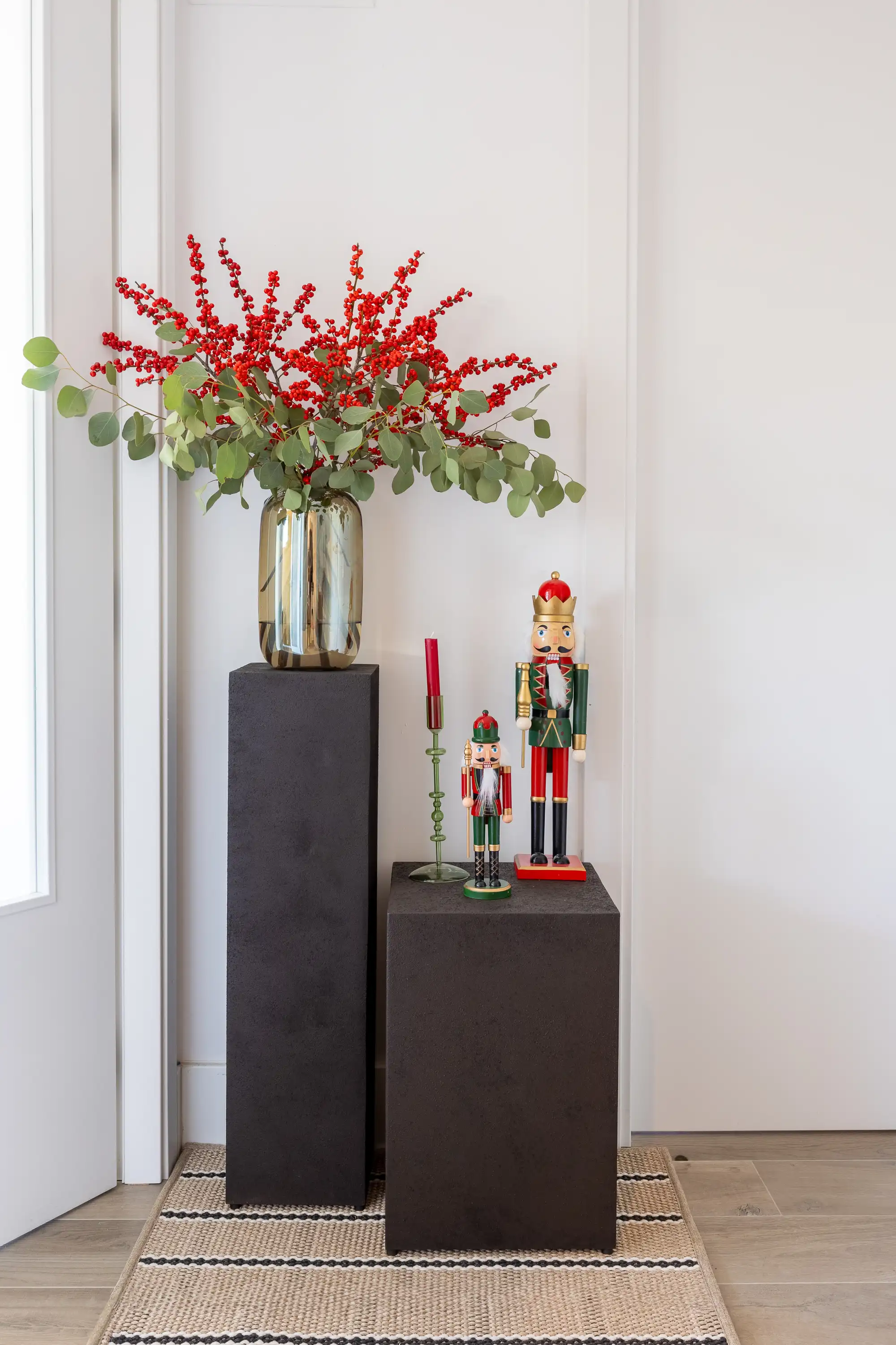 En la entrada, María del Valle ha creado este rincón ideal para estos días de Navidad. Peanas de Zara Home, detalles decorativos de El Corte Inglés, alfombra de Rols y arreglo floral del estudio.