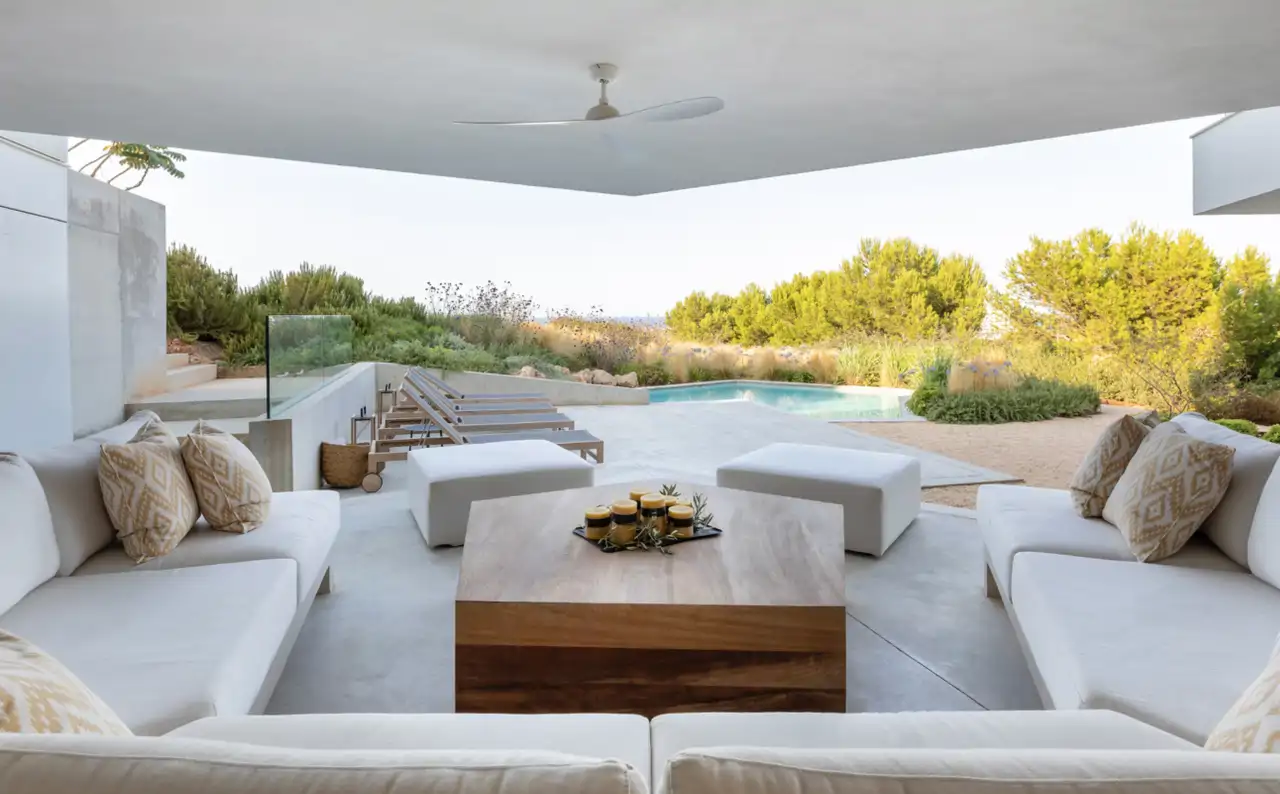 porche cubierto con jardin y piscina y sofas blancos