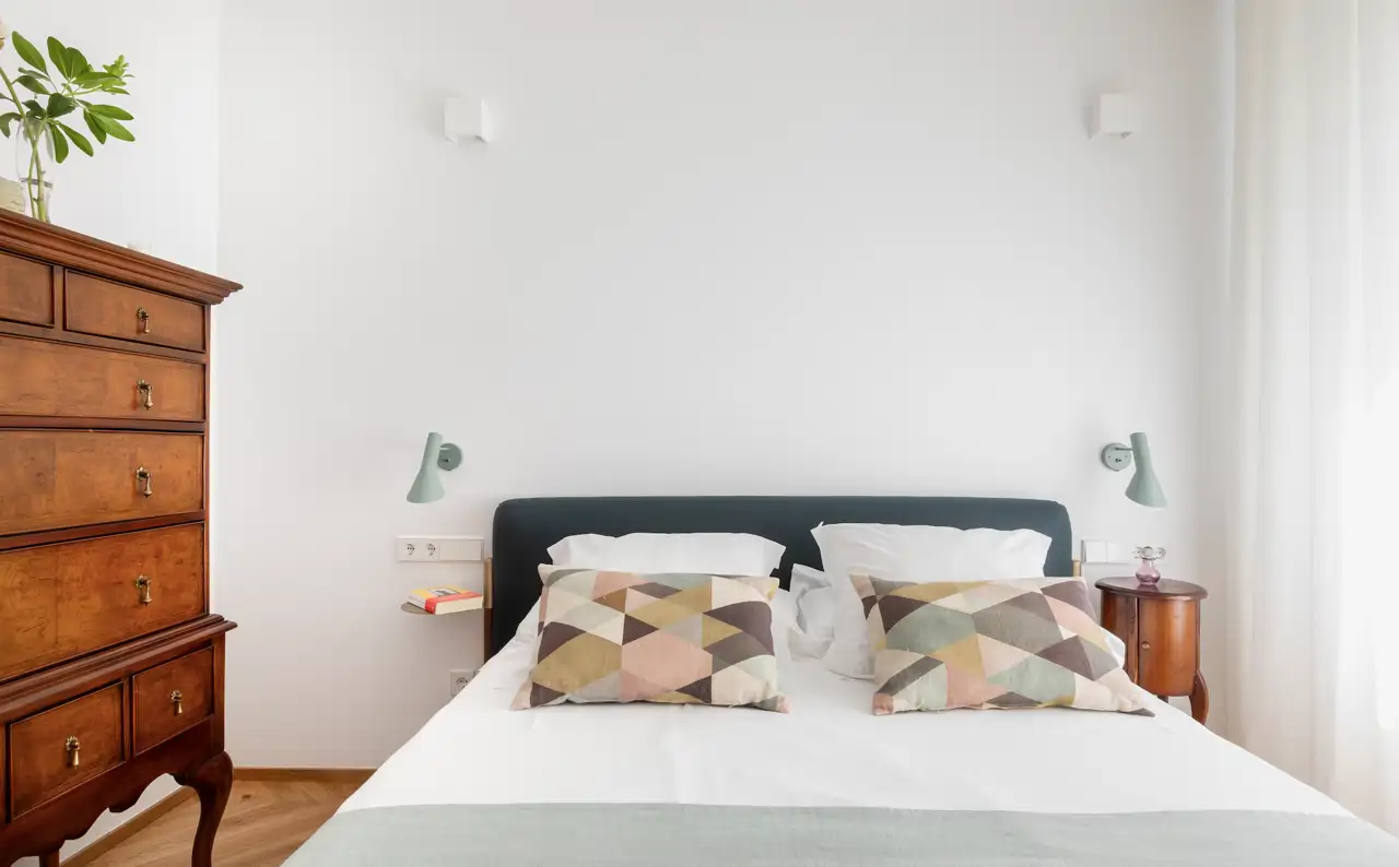 Un dormitorio con paredes blancas y una cómoda antigua como protagonista