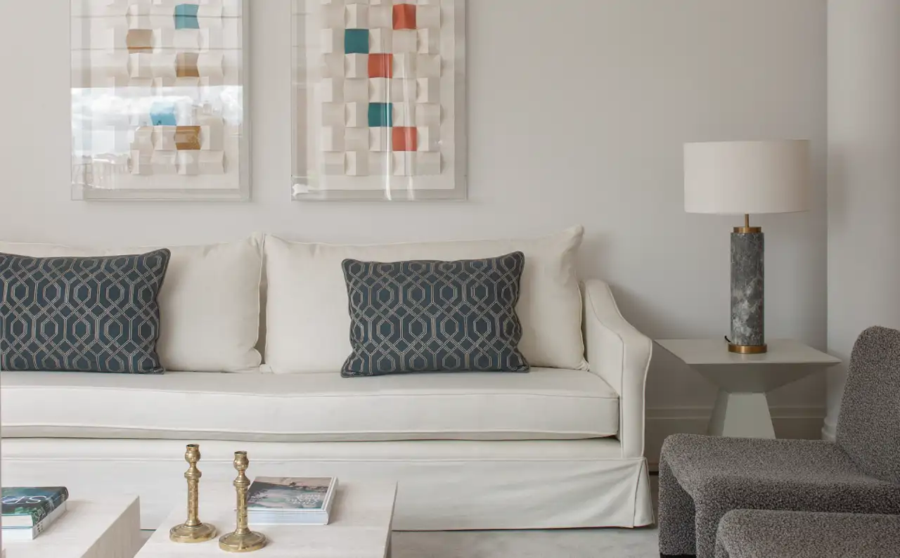 Salón con sofá blanco y pared de sofá con cuadros