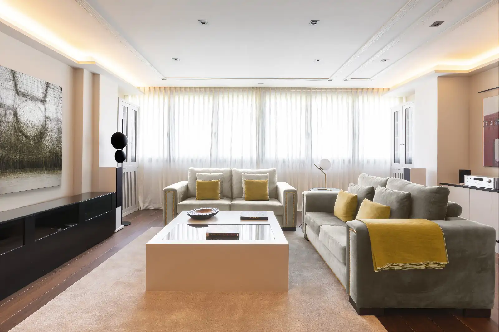 Salón con cortinas de tipo visillo y cojines amarillo mostaza