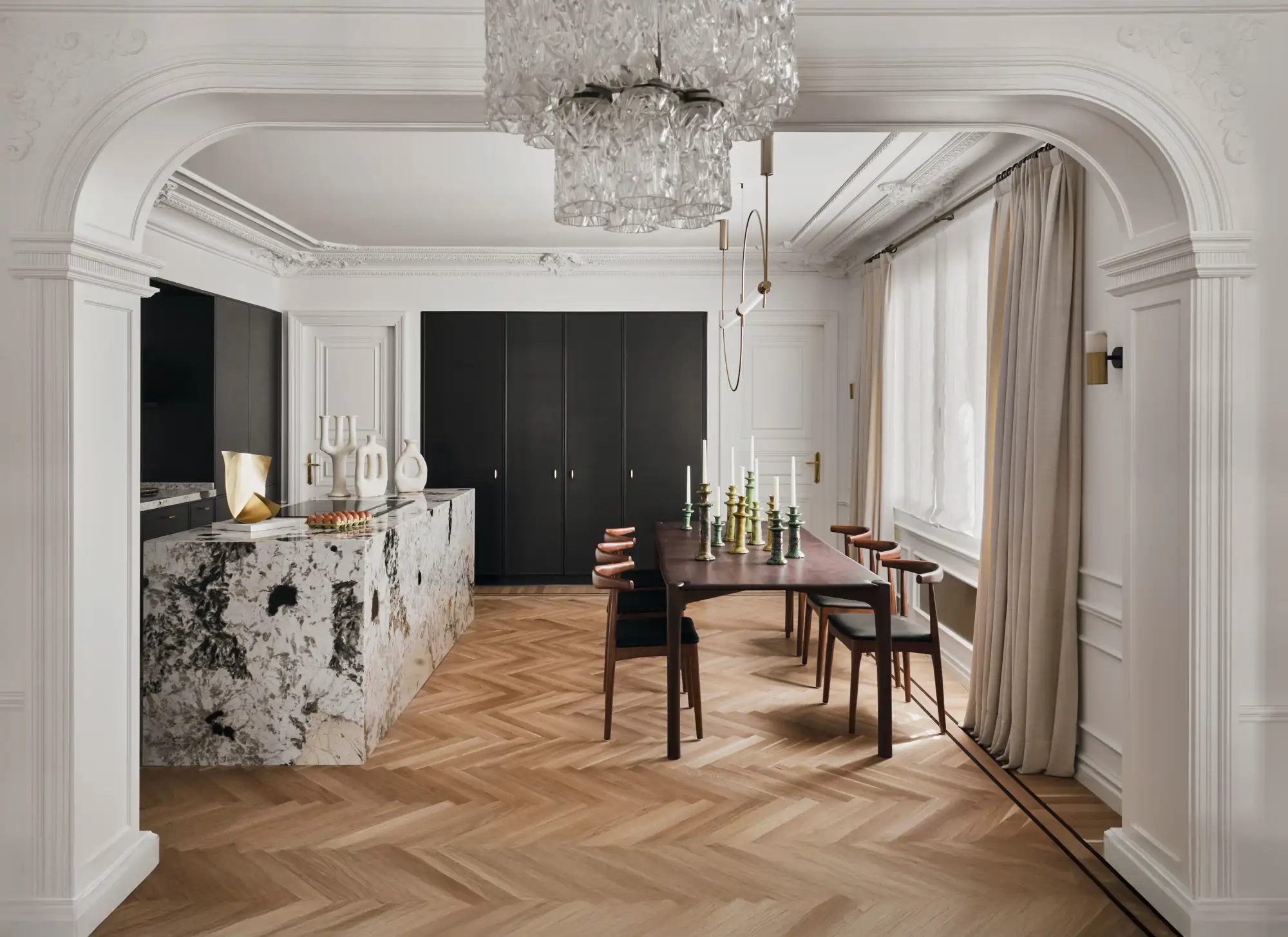 Cocina con isla de mármol, lámpara de araña y mesa de comedor de madera oscura