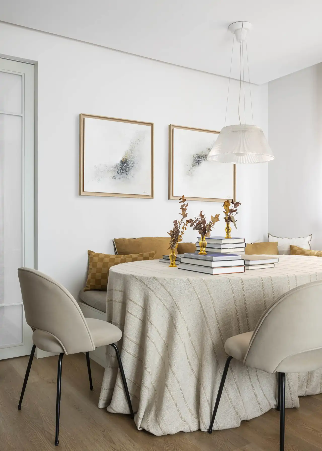 Comedor blanco con lámpara, mesa, butacas y cuadro