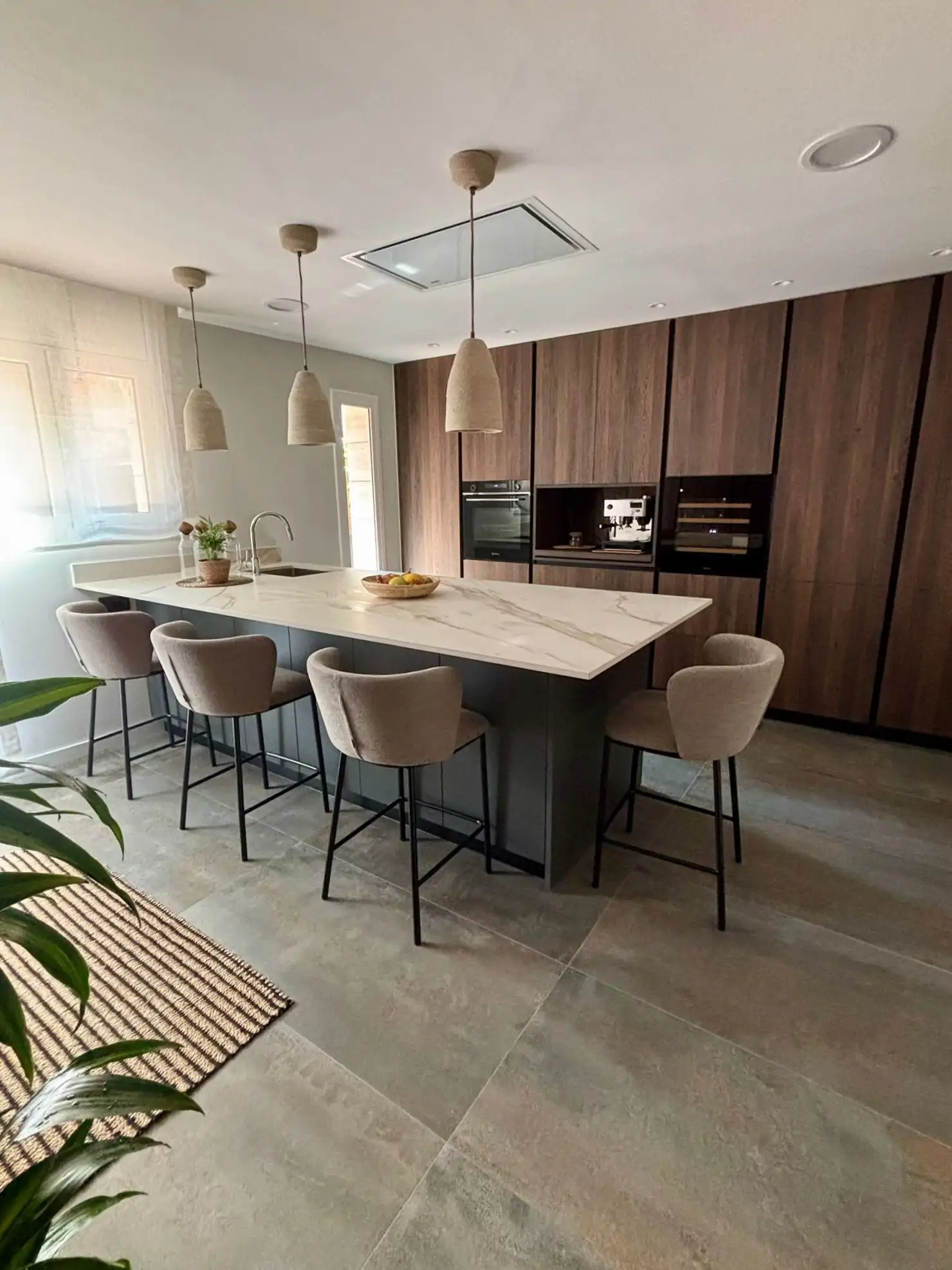 Cocina con madera oscura y península de mármol