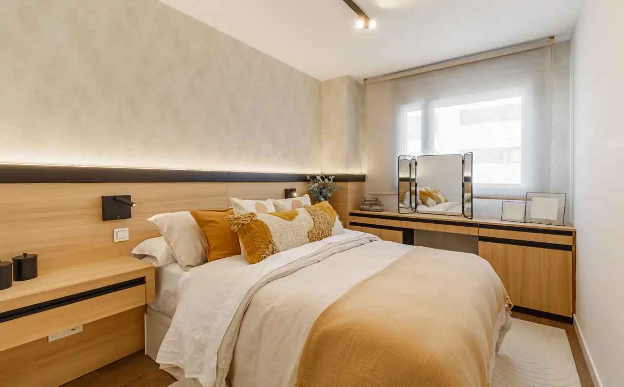 Un dormitorio con cabecero de madera y con textiles que combinan el blanco y el mostaza