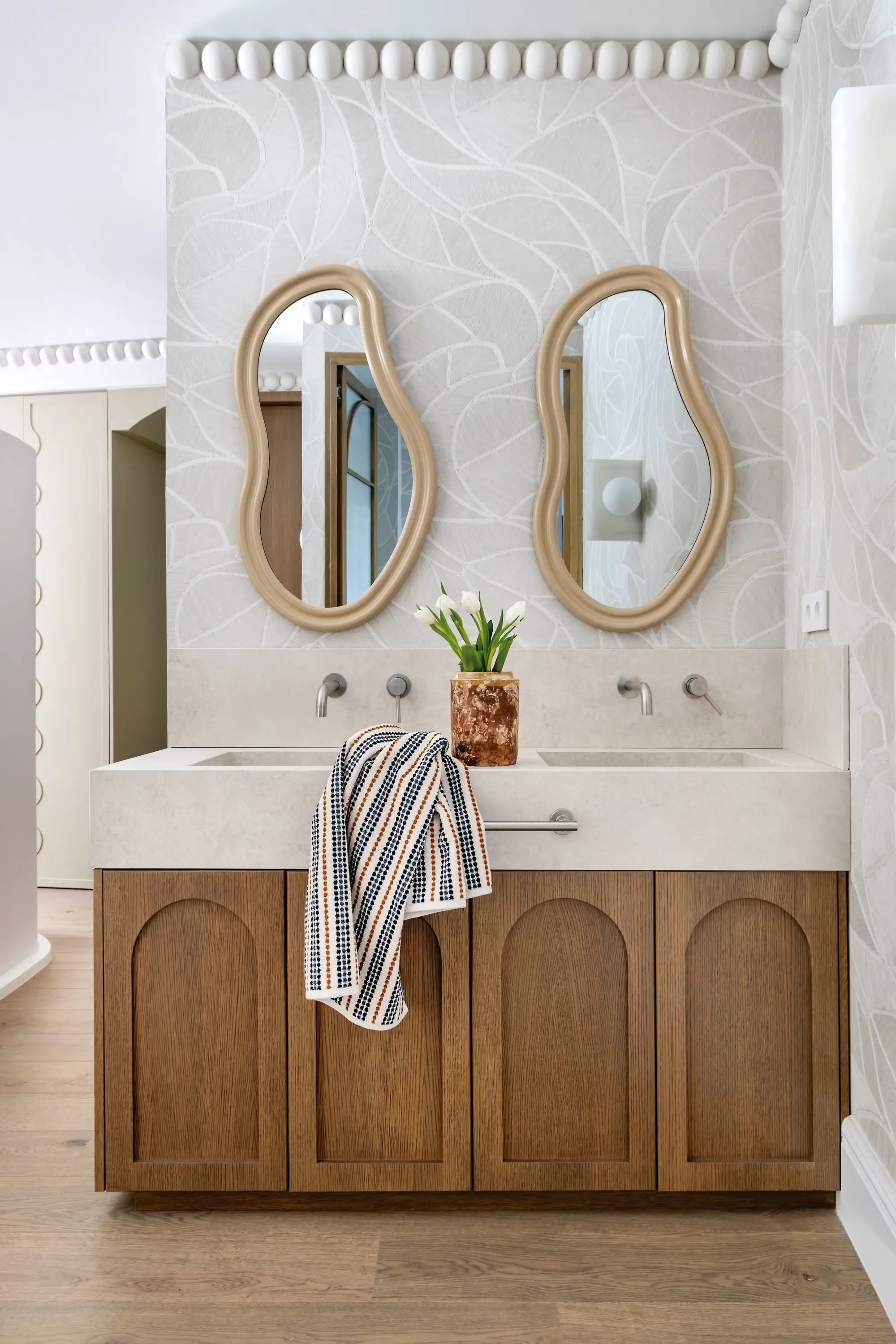 Baño con mueble de madera y espejos curvos